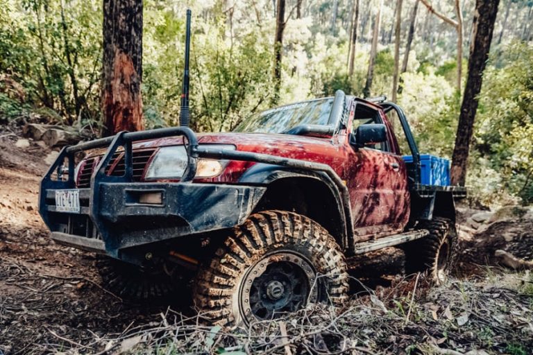Mud-covered maroon Patrol cab-chassis with 37-inch mud tyres on a steep rutted trail near Kilmore.