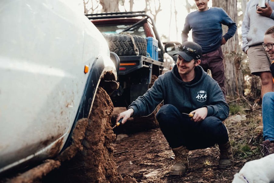 Mitch from MBC 4X4 Solutions on his knees in the mud helping mates recover a bogged 4WD in Central Victoria.