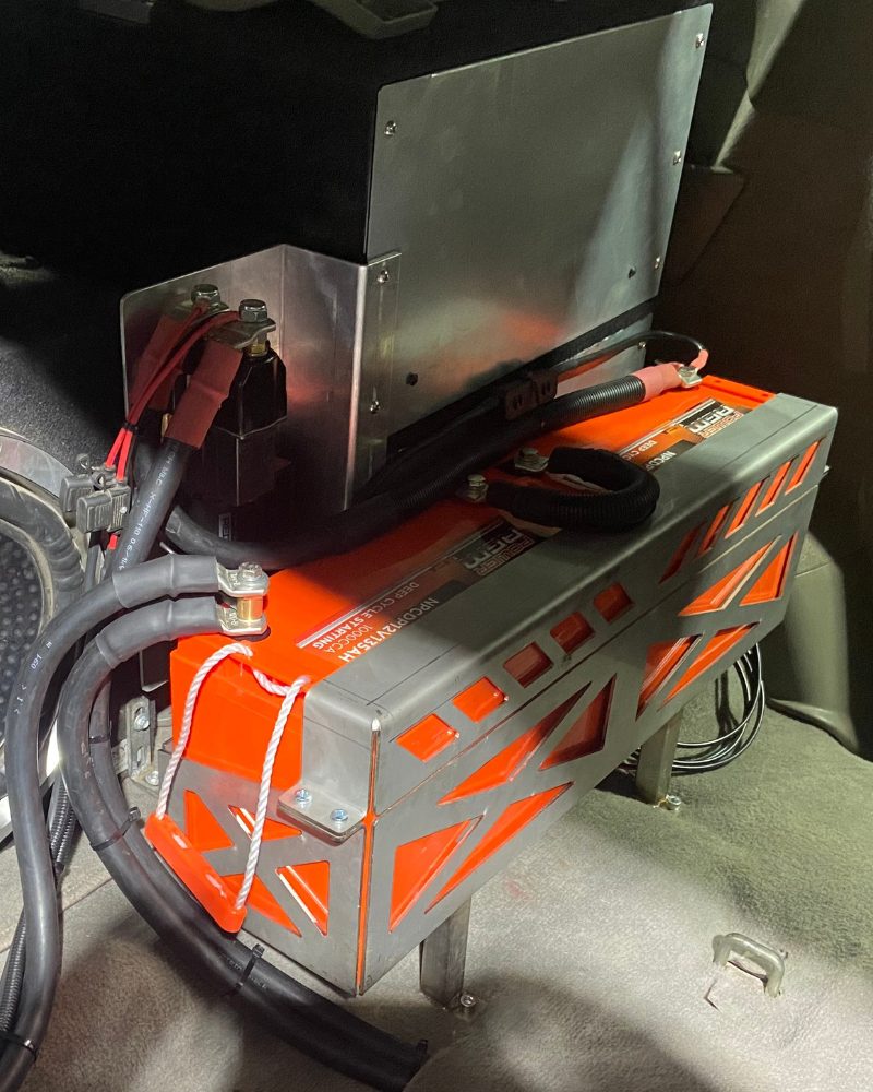 Right side of the twin 135Ah AGM 24-volt winch battery setup in a custom cradle behind the rear seats of a Nissan GU Patrol, with a Red Arc DC-DC charger, by MBC 4X4 Solutions in Eaglehawk